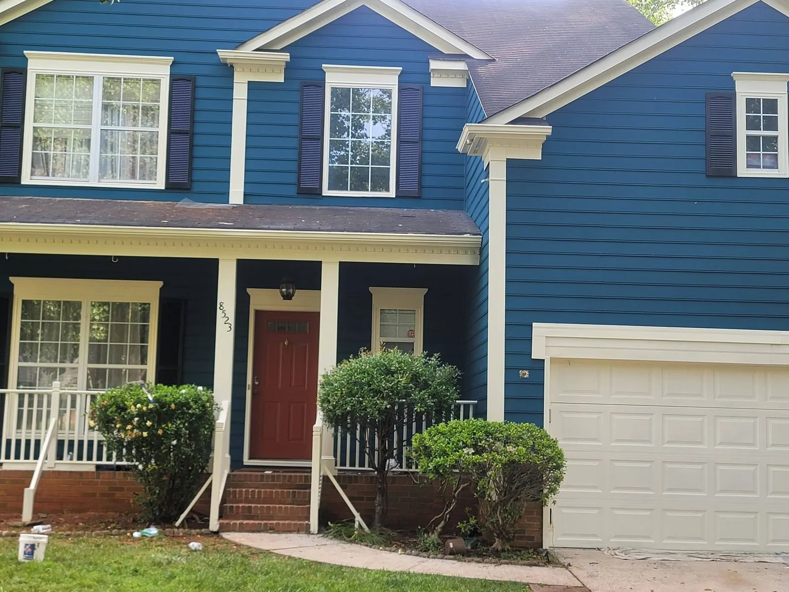 The same house repainted deep blue with white trim and a red front door