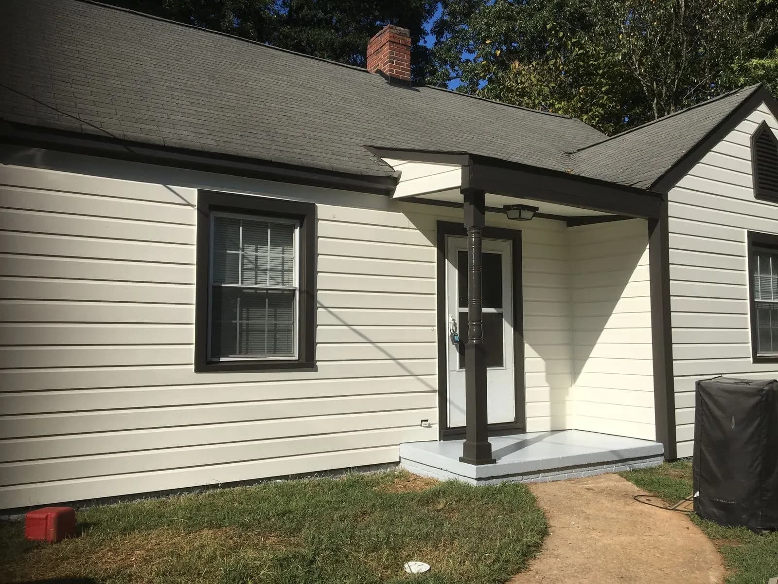 The same cottage painted white with black window trim and porch posts