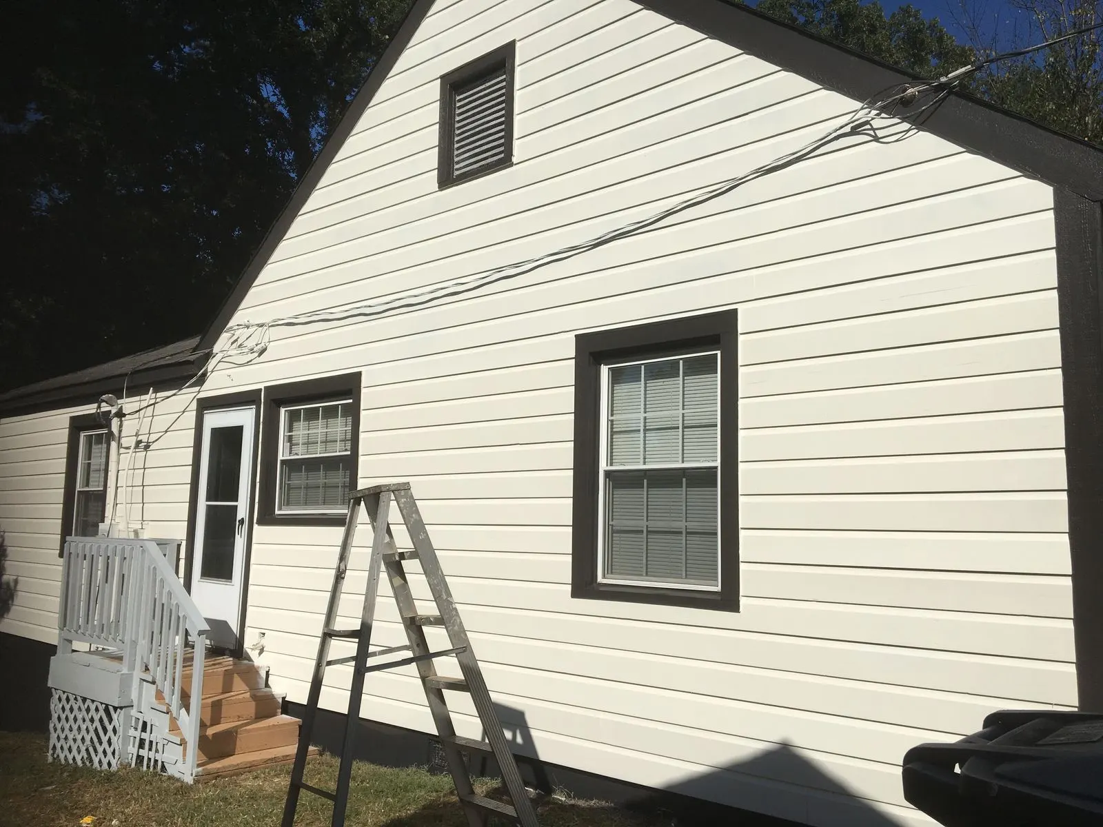 Back of a cottage painted white with black window trim