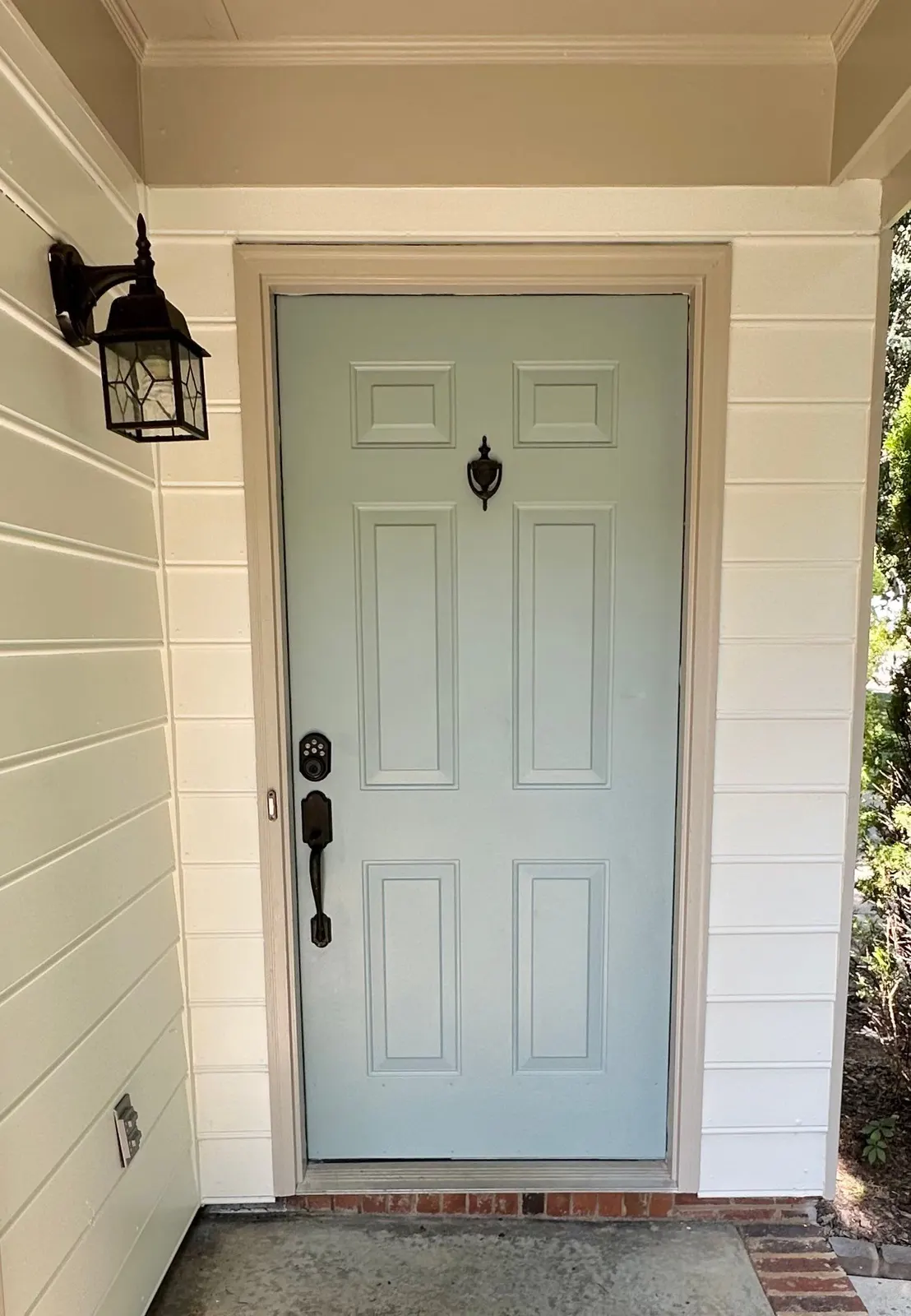 Front door painted pale blue with a black lantern beside it