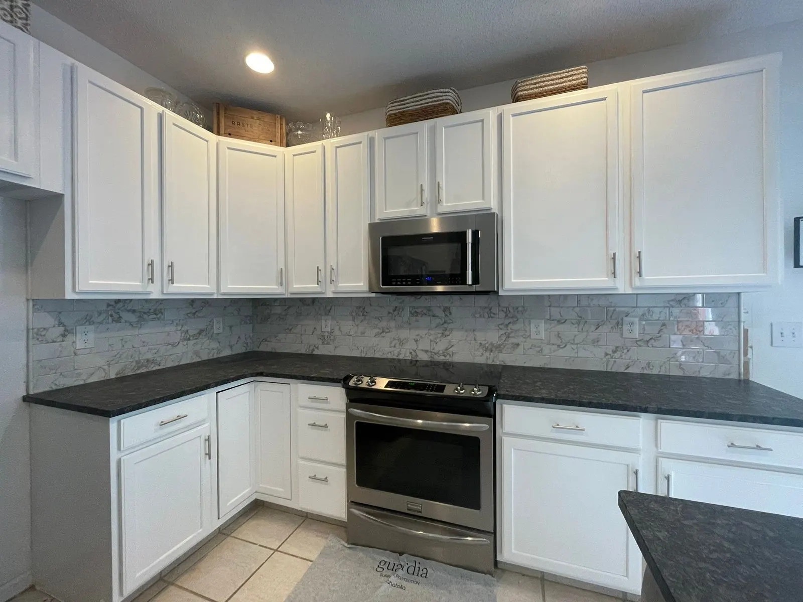 Kitchen with white painted cabinets, dark counters and stainless appliances