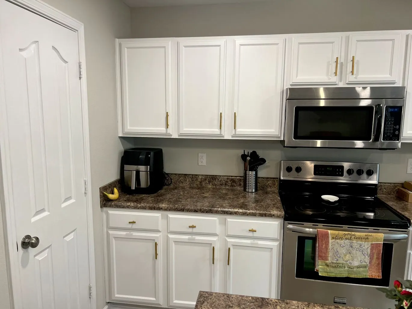 Kitchen with white painted cabinets, brass pulls and stainless appliances