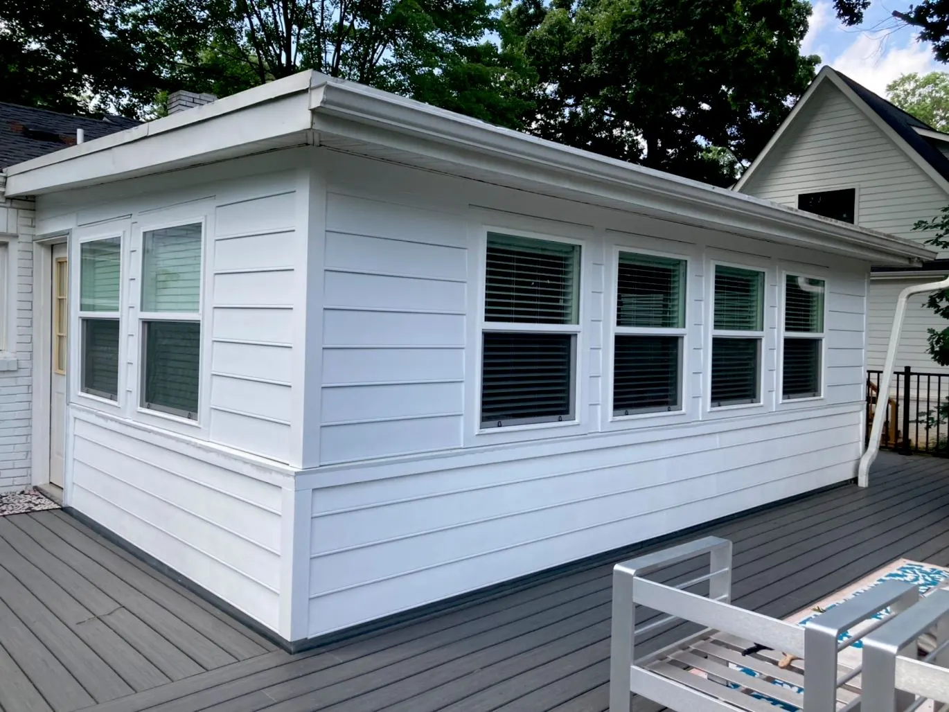 White painted sunroom siding beside a deck