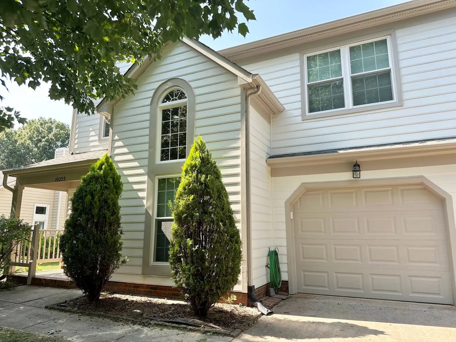 White two-story house with an arched window and attached garage